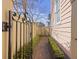 Side yard with brick walkway, lush green hedges, and a decorative gate offering privacy at 249 Ashley Ave, Charleston, SC 29403