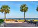 Beautiful waterfront view with a sailboat gliding on the water, framed by palm trees and benches at 32-E Prioleau St, Charleston, SC 29401