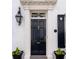 Elegant front door featuring fluted columns, transom window, and decorative black flower pots at 35 Tradd St, Charleston, SC 29401