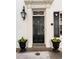 Elegant front door with classic columns, decorative transom, and charming floral planters at 35 Tradd St, Charleston, SC 29401
