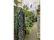 Ornate black metal gate flanked by brick pillars and lush greenery leads into a verdant garden at 35 Tradd St, Charleston, SC 29401