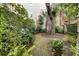 Mossy brick path winds through a lush garden with mature trees and verdant foliage at 35 Tradd St, Charleston, SC 29401