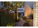 Brick path winds through a lush garden with mature trees, shrubs, and ambient lighting at 35 Tradd St, Charleston, SC 29401
