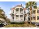 Beautiful two-story home with double balconies, white columns, red roof and landscaped yard with a palm tree at 47 Ashley Ave, Charleston, SC 29401