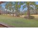 Scenic view of a lush backyard with tall pine trees, green grass, and a tranquil pond in the distance at 7 Dogwood Ln, Walterboro, SC 29488