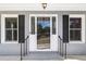The main entrance is flanked by two windows with black shutters and black iron railings at 782 Bonham Dr, Charleston, SC 29412