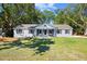 Charming gray brick home featuring a manicured lawn, mature trees, and a welcoming front porch with a swing at 782 Bonham Dr, Charleston, SC 29412