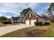 View of a two-car garage featuring a brick exterior with black shutters, a concrete driveway, and mature trees at 109 Presidio Bnd, Summerville, SC 29483