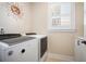 This laundry room features a washer, dryer, white shaker cabinets, and is well-lit by a window at 115 Bluff Isle Ct, Summerville, SC 29486