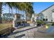 Inviting backyard patio with a stone fireplace, palm trees, and comfortable seating, ideal for relaxation at 115 Bluff Isle Ct, Summerville, SC 29486