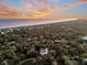 Breathtaking aerial view of a coastal home surrounded by lush trees, with the ocean stretching to the horizon at sunset at 129 Sparrow Dr, Isle of Palms, SC 29451