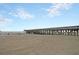 Expansive beach scene featuring a long pier and a calm ocean under a partly cloudy blue sky at 129 Sparrow Dr, Isle of Palms, SC 29451