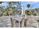 Outdoor deck area featuring a dining table, cushioned chairs, white umbrella, and view of surrounding foliage at 129 Sparrow Dr, Isle of Palms, SC 29451