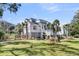 Beautiful two-story home with white siding, a landscaped yard, and palm trees at 129 Sparrow Dr, Isle of Palms, SC 29451