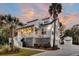 Elegant two-story white home with covered porch, complimented by palm trees and meticulous landscaping at 129 Sparrow Dr, Isle of Palms, SC 29451