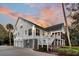 Elegant two-story home featuring a three-car garage, a porch, and manicured landscaping at 129 Sparrow Dr, Isle of Palms, SC 29451