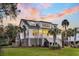 Stately two-story home with well-maintained lawn, mature palm trees, and inviting front porch at 129 Sparrow Dr, Isle of Palms, SC 29451