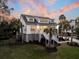 Inviting two-story beach house with a white exterior, front porch, and scenic sunset at 129 Sparrow Dr, Isle of Palms, SC 29451