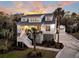 Beautiful two-story home featuring a white exterior, landscaping, and a well-lit entrance at 129 Sparrow Dr, Isle of Palms, SC 29451