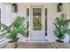 Charming front entrance with glass paneled door, sconces, and potted palm trees for added curb appeal at 129 Sparrow Dr, Isle of Palms, SC 29451