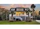 Charming two-story home with a welcoming front porch, complemented by lush landscaping and palm trees at 129 Sparrow Dr, Isle of Palms, SC 29451