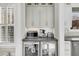 Wet bar featuring cabinets with glass display shelving, stainless steel appliances, and dark countertops at 129 Sparrow Dr, Isle of Palms, SC 29451