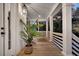 Comfortable covered porch with wood flooring, classic railing, and decorative potted plants at 129 Sparrow Dr, Isle of Palms, SC 29451