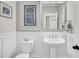 Charming powder room featuring a pedestal sink, white wainscoting, and decorative mirror at 129 Sparrow Dr, Isle of Palms, SC 29451