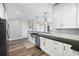 Modern kitchen with stainless steel appliances, farmhouse sink, white cabinets, and dark countertops at 145 Pier View St # 403, Charleston, SC 29492