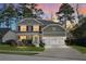 Charming two-story home with manicured lawn, mature trees, and a two-car garage at sunset at 188 Donning Dr, Summerville, SC 29483