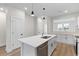 A bright kitchen features an island with sink and white cabinets with dark hardware at 2191 Helm Ave, North Charleston, SC 29405