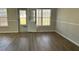 Bright living room with wood-look floors, neutral walls, and natural light from the windows and door to the outside at 5082 Westview St, North Charleston, SC 29418