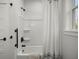 Clean, white bathtub and shower combo with black hardware and curtain with natural light from the window at 5585 Wire Road, Branchville, SC 29432