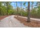 Gravel driveway winding through a lush green forest landscape under a bright blue sky at 5585 Wire Road, Branchville, SC 29432