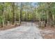 Gravel driveway leading to metal gate with wood posts, surrounded by tall trees at 5585 Wire Road, Branchville, SC 29432