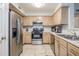 Well-lit kitchen featuring stainless steel appliances, tile floor, and light wood cabinets at 700 Daniel Ellis Dr # 13302, Charleston, SC 29412