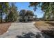Inviting home exterior with a winding driveway and lush landscaping, blending seamlessly with nature at 7527 Ladys Secret Ln, Awendaw, SC 29429