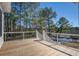 Back porch with wooden floors and white rails overlooking the lake and trees at 7527 Ladys Secret Ln, Awendaw, SC 29429