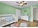 Well-lit Bedroom featuring green walls, wood floors, white furniture, ceiling fan and baby decor at 108 Gambels Ln, Summerville, SC 29485