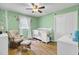 Bedroom with green walls, rocking chair, white crib, ceiling fan, and hardwood floors at 108 Gambels Ln, Summerville, SC 29485