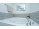Close-up of a luxurious soaking tub with grey tile accents and a soothing seascape artwork above at 1089 Fort Johnson Rd, Charleston, SC 29412