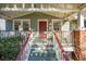 Close up of charming home featuring a cozy front porch, brick accents, and mature trees at 12 Poplar St, Charleston, SC 29403