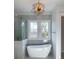 Serene bathroom with a soaking tub next to a window with a view, and a modern light fixture at 1468 Alligator Creek Ct, Awendaw, SC 29429