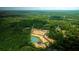Picturesque aerial view of land featuring a tranquil pond surrounded by flourishing trees and freshly paved roads at 201 Seele St, Lincolnville, SC 29485