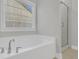 Bathroom with a large soaking tub next to a tiled shower with glass door and ample natural light at 207 Calm Water Way, Summerville, SC 29486