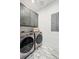 Bright laundry area featuring front-loading washer and dryer, gray cabinetry, and modern light fixture at 231 Bayview Dr, Mount Pleasant, SC 29464