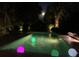 A stunning outdoor pool with glowing orbs, illuminated landscaping, and a serene nighttime ambiance at 24 Commons Ct, Isle of Palms, SC 29451