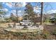 Secluded backyard with mature trees, stone patio with conversation furniture surrounding a fire pit, and a grassy lawn at 3334 Merion Pl, Mount Pleasant, SC 29466