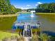 Scenic view of a pond with a wooden dock and fountain surrounded by lush greenery and neighborhood homes at 1208 Red Buckeye Ct, Moncks Corner, SC 29461