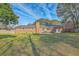 Expansive brick home backyard featuring a patio, mature trees, and lush green lawn under a sunny, blue sky at 1247 Oakcrest Dr, Charleston, SC 29412